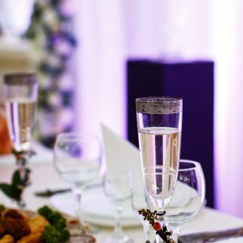 Champagne flute decorated with little branch stands on dinner table